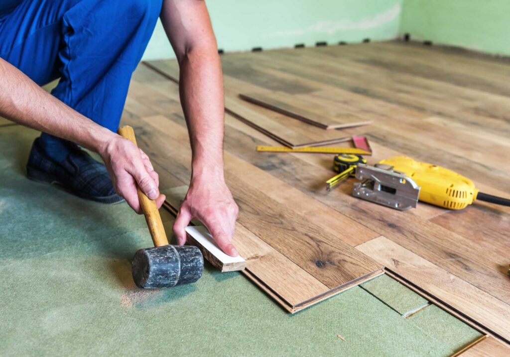 Flooring contractor uses a rubber mallet to install wood flooring