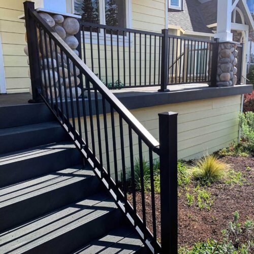 Composite deck stairs and metal handrailing on the front of a yellow house