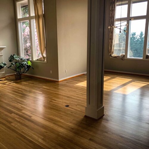 Wooden floors in a large living room with two large windows