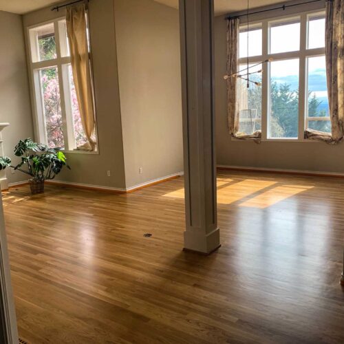 Wooden floors in a room with two large windows and a pillar