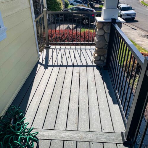 Composite deck with metal railing on a yellow house