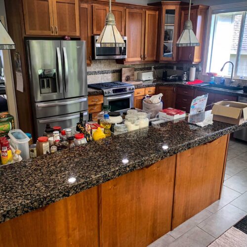 Black granite countertop area in a kitchen full of food items