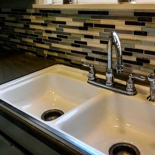 Kitchen sink area with black and white tiled back splash