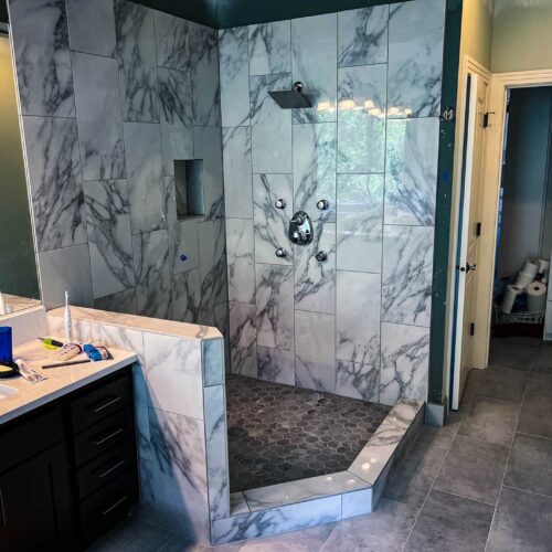 Walk-in shower with marble walls in a bathroom