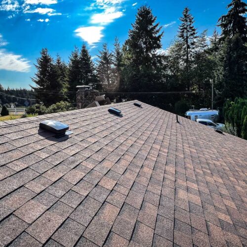 newly replaced beige colored roof shingles on a roof with skylights.