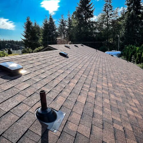 newly replaced beige colored roof shingles on a roof with skylights.