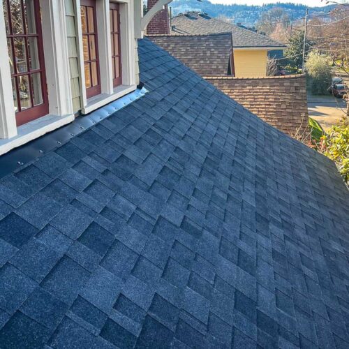 Dark shingled roof under windows