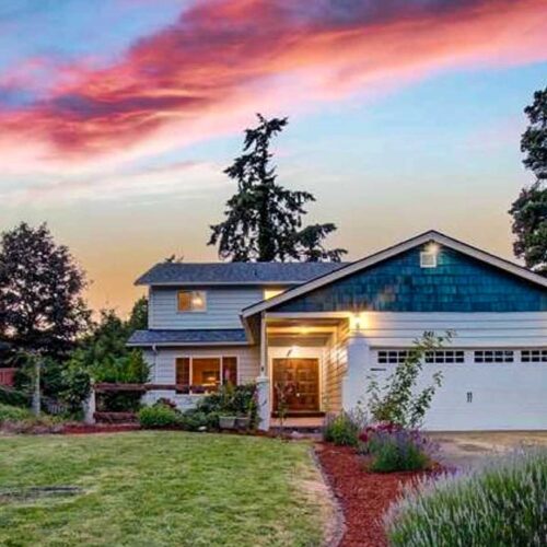 Red sunset clouds over a two story grey and blue home