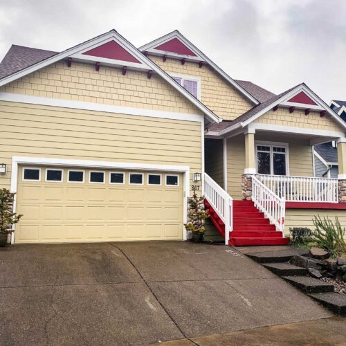 Yellow two story residential home with a red staircase