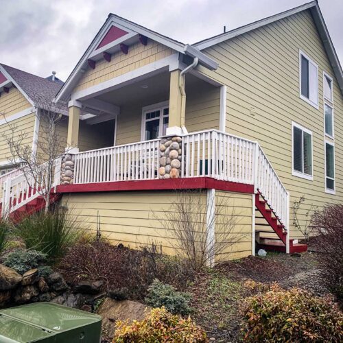 Yellow two story residential home with a white handrail on the staircase