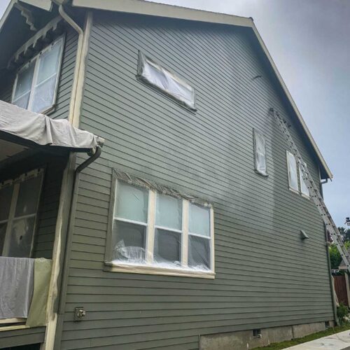 Side of a two story home being painted a olive green color