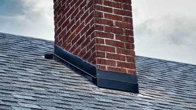 New asphalt roof shingles around a brick chimney