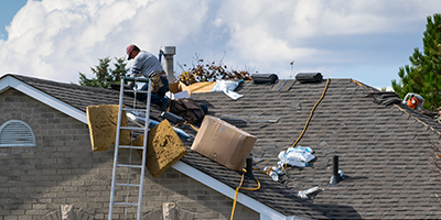 Roofing worker on the roof of a 2-story family house for roof installation, new asphalt shingles