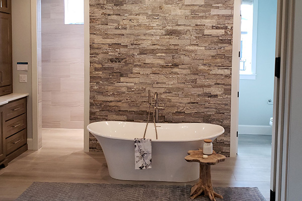 contemporary bathroom remodel with a white tub, stone wall, and new paint job